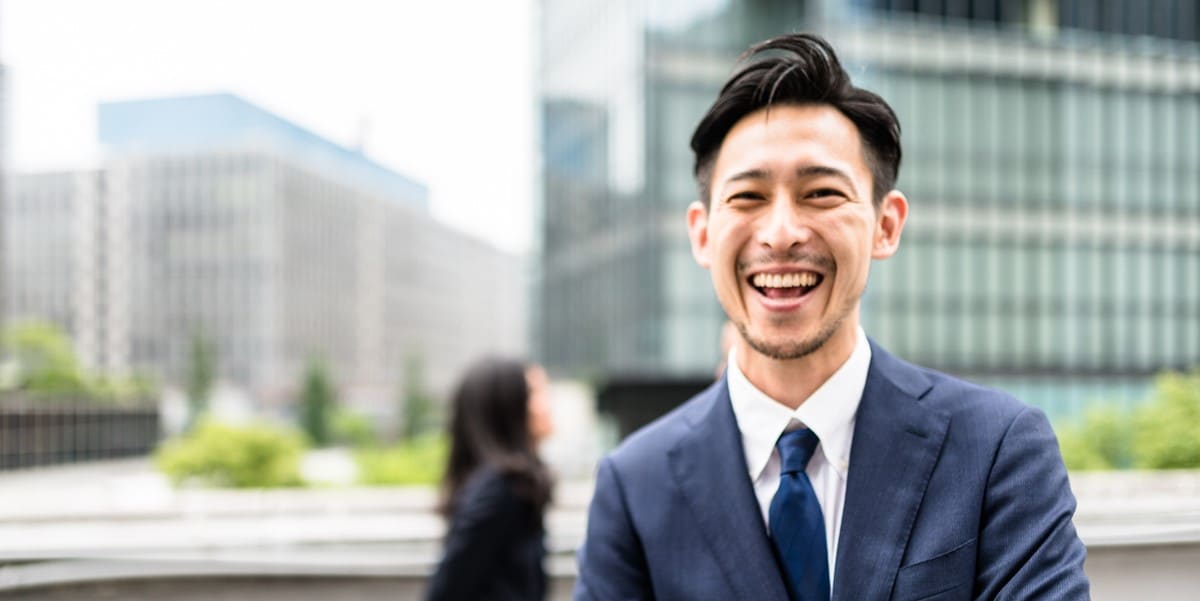 professional man smiling, in front of office buildings