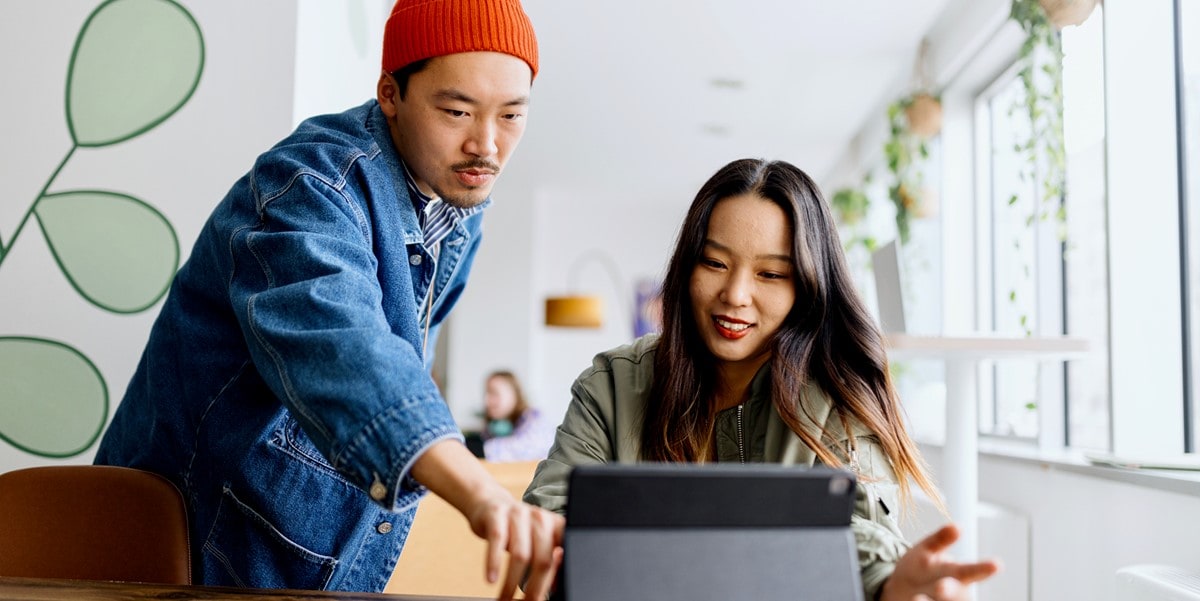 man and woman working in office, looking at computer screen